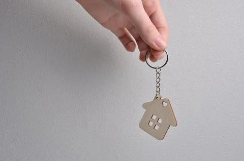 Keychain in the shape of a house in hands. Stock Photos