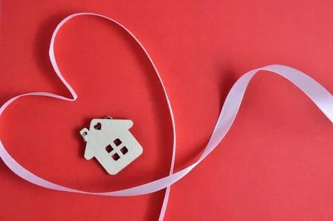 Keychain in the shape of a house on a red background. Pink ribbon. Valentines Stock Photos
