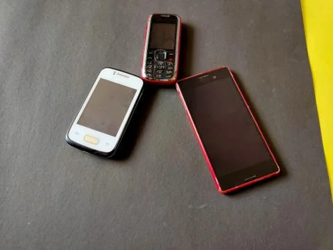 Keypad mobile and two smart phones placed like triangle.Isolated on black bac Stock Photos