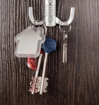 Keys and House shaped keychain on wooden background Stock Photos