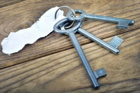 Keys with empty note on wooden table Photos