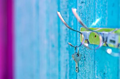 Keys hanging from a hook on the old painted wooden wall outside Stock Photos