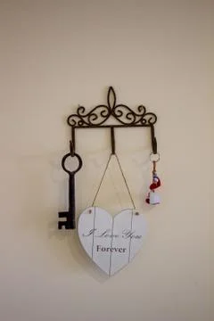 Keys hanging from hooks, on light wall background Stock Photos