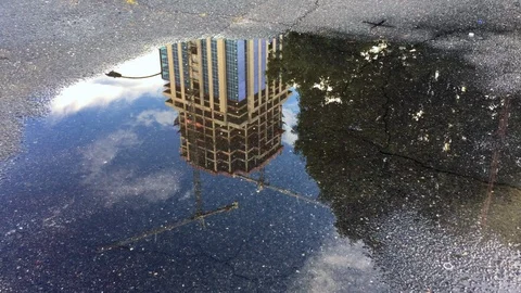Keys tossed in a puddle reflecting an office building under construction Stock Footage 94542023