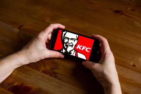 Kfc logo sign application screen on mobile phone online retail service, hands on 库存照片