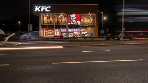 A KFC Restaurant at night timelapse with passing traffic and people inside Video stock 265504151