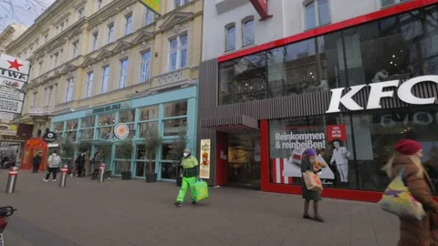 KFC restaurant on a street corner with crowd of people passing by Stock Footage 165357609