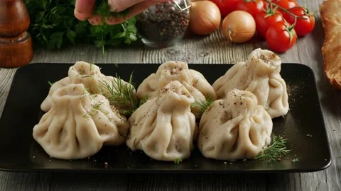 Khinkali served on a platter. Presentation of the dish. The cook sprinkles th Stock Footage 147870767