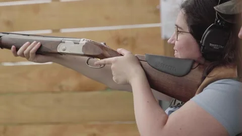 Kick back from shotgun as woman pulls triggered and fires. Handheld Stock Footage 256736357