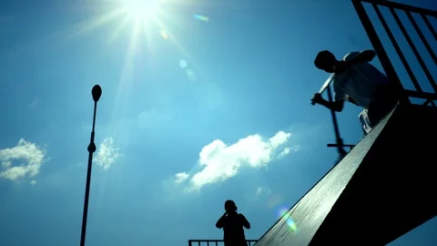 Kick scooter silhouettes making tricks in the city skate park. Slow motion. Vidéo 122393362