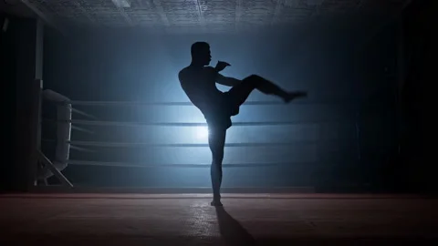Kickboxer training in low light gym. Muay thai fighter practicing shadow boxing. Stock Footage