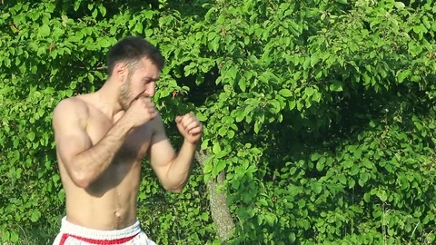 Kickboxer trains blows in front of a big battle. in the park Stock Footage 77215176