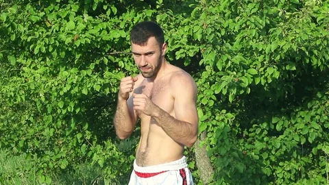 Kickboxer trains blows in front of a big battle. in the park Stock-Footage 77250203