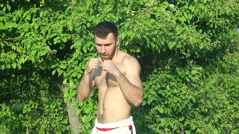 Kickboxer trains blows in front of a big battle. in the park Stock-Footage 77263728