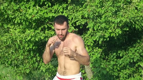 Kickboxer trains blows in front of a big battle. in the park Stock Footage 77266086