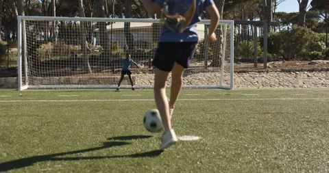 Kicker running up, striking soccer ball on turf trying to score while goalkeeper Stock Footage 339651599