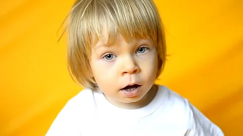 The kid is 2 years old with blonde hair, dressed in a white T-shirt and yellow Stock Footage 251019091