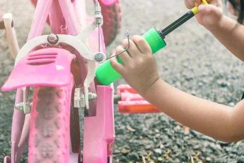 Kid acting like using air pumping inflate her bicycle tire Stock Photos