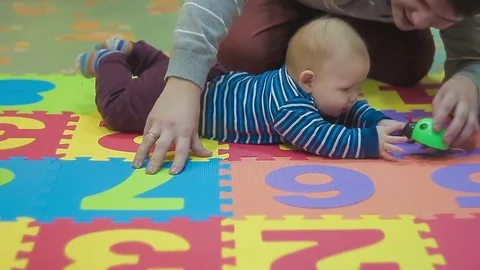 Kid and His Dad Playing With Green Toy on Colored Carpet Stock Footage 72320646