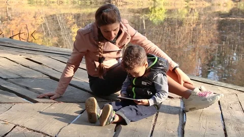 Kid and his mom using smartphone in the autumn park	 Stock Footage 124009123