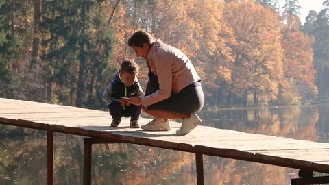 Kid and his mom using smartphone in the autumn park Stock Footage 124009182