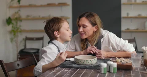 Kid and mom spend time together doing creative work. Child boy kisses mom. Slow Stock Footage 156384977