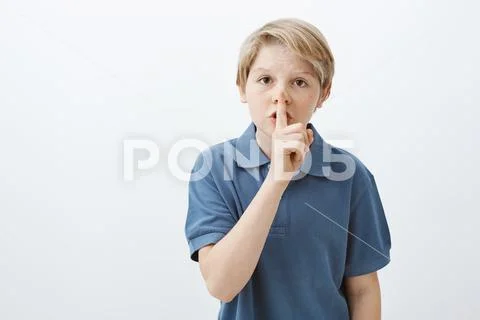 Kid asking friend keep secret. Portrait of serious cute blond male child in blue Stock Photos