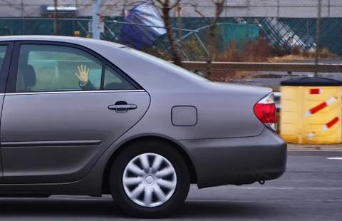 Kid in the back of the car slapping hand on the window creating unwanted trou Stock Photos