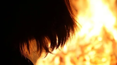 Kid in beanie gets too hot while standing by the massive fire Stock Footage 122307542