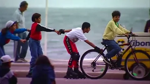 Kid on bicycle tows friends on rollerskates Video stock 80163664