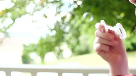 Kid blowing bubble and slow motion close up on hand with tree in the background Stock Footage 207339354