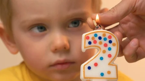 Kid is blowing out the festive candle on birthday cake celebrating at home Видео 128384582