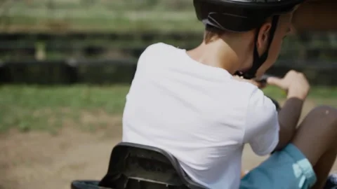 Kid boy back view  driving white children go-kart in park summer time Stock Footage 201294742