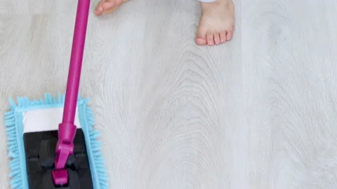 Kid boy cleaning the laminate gray floor with green wet mop 스톡 동영상 210222282