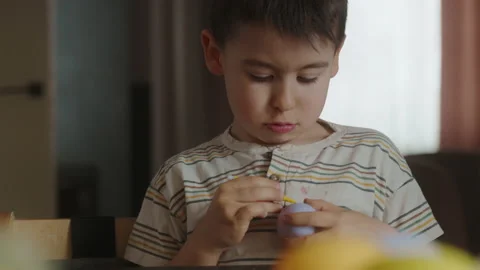 Kid boy coloring eggs for Easter holiday in domestic kitchen, indoors. Child Stock Footage 239506870