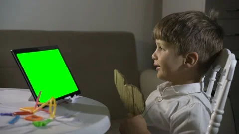 Kid boy communicates on a tablet with a remote connection greens screen Stock Footage 202010883