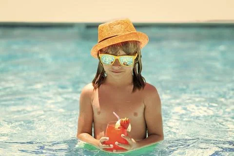 Kid boy drinking coctail in the pool. Little child boy in swimming pool. Kids Fotos Stock