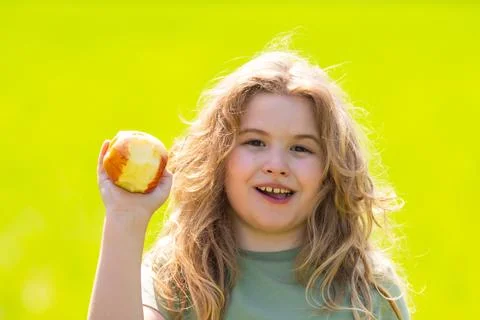 The Kid boy eats an apple. Ripe fruit for kids. Kid bites apple. The boy enjoys Stock Photos