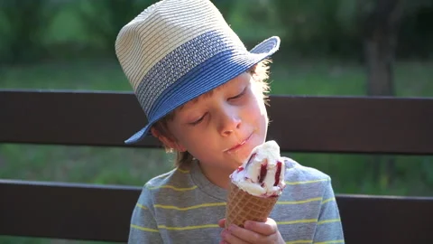 Kid Boy eats Ice cream Cone, licks it with Tongue Video stock 135011397