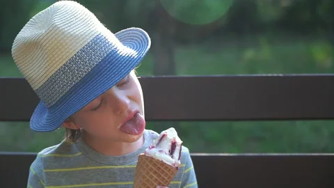 Kid Boy eats Ice cream Cone, licks it with Tongue Video stock 135011486