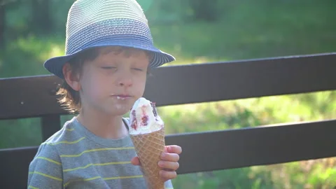 Kid Boy eats Ice cream Cone, licks it with Tongue Video stock 135012456