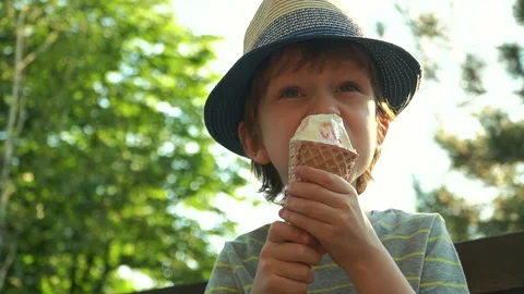 Kid Boy eats Ice cream Cone, licks it with Tongue Video stock 135014456