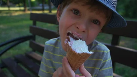 Kid Boy eats Ice cream Cone, licks it with Tongue Video stock 135019253