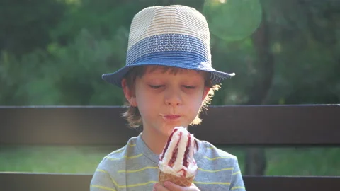 Kid Boy eats Ice cream Cone, licks it with Tongue Video stock 135023893