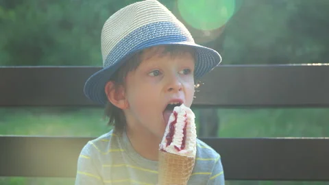 Kid Boy eats Ice cream Cone, licks it with Tongue Video stock 135024444