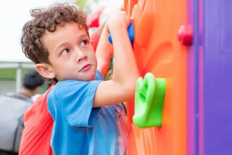 Kid boy having fun to play on children's climbing toy at school playground,ba Stock Photos