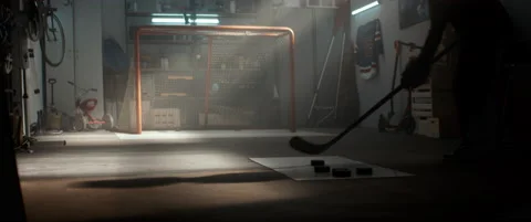 Kid boy hockey player practicing shots inside a covered garage at home Stock Footage 145182408