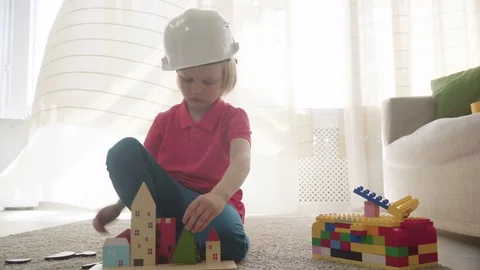 Kid boy imitates engineer constructing a building using colorful meccano Stock Footage 78560693