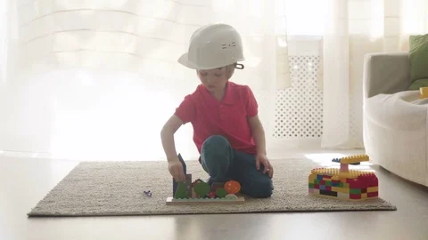 Kid boy imitates engineer constructing a building using colorful meccano Stock Footage 78560702
