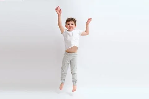 Kid boy jumping with a happy expression and hands raised on a white backgroun Stock Photos
